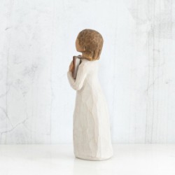 Faceless girl figurine wearing white dress holding brown book