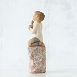 Front view of boy with brown hair sitting on a stump while holding a small potted plant to his chest