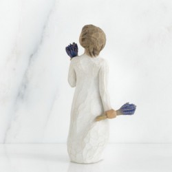 Brunette girl figurine in white dress holding two sets of blue flowers in each hand