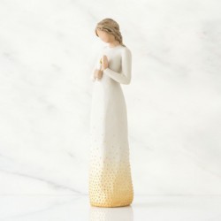 Faceless woman figurine wearing all white dress with her hands holding a candle