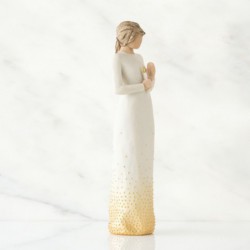 Faceless woman figurine wearing all white dress with her hands holding a candle