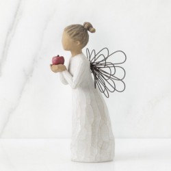 Front view of angel with brown hair in high pony tail leaning forward and holding a red apple up to her face with both hands