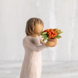 Front view: standing figure with short brown hair in cream dress holding out terracotta pot of orange milkweed plant