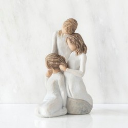  figurine of three females in cream dresses: one standing with arm around kneeling female