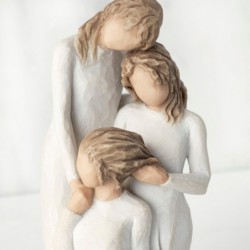  figurine of three females in cream dresses: one standing with arm around kneeling female