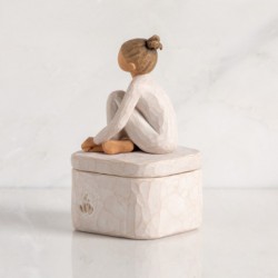 3-d carving of girl in cream leotard sitting atop lid